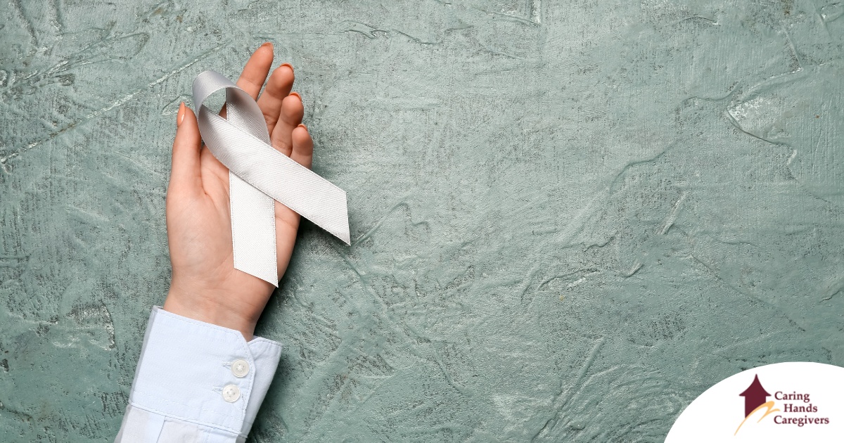 A woman holds a silver ribbon, representing Parkinson’s Awareness Month.