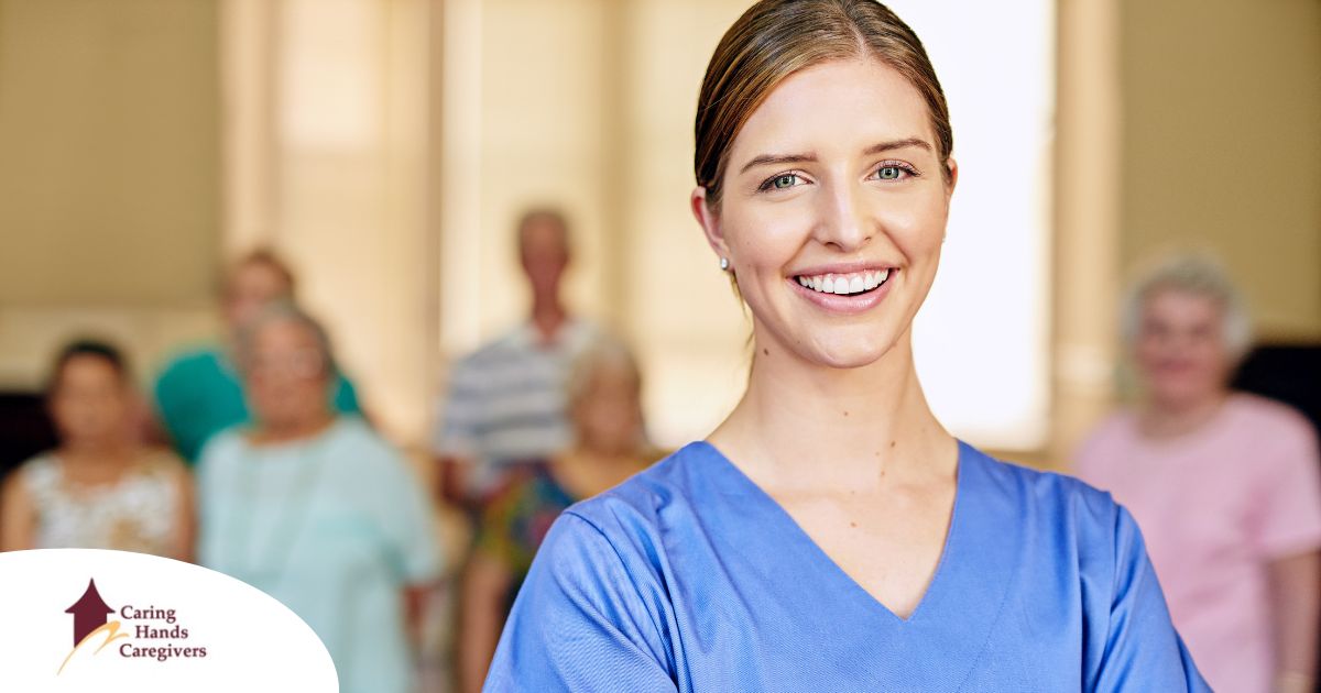 A professional caregiver smiles with seniors behind her, showing how a job with a caregiver agency can be a good choice.