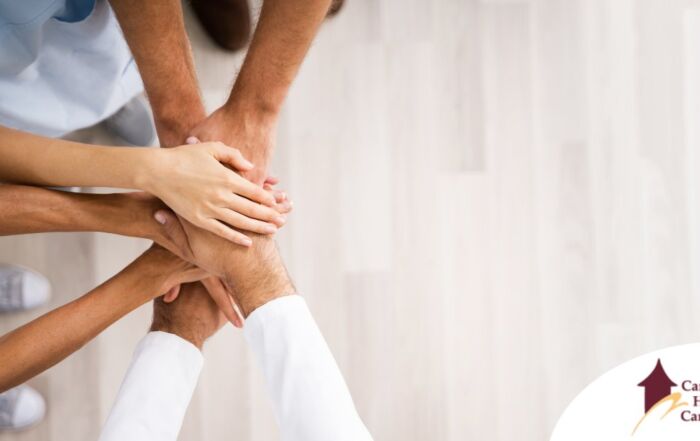 Several hands join together representing collaboration among caregivers.