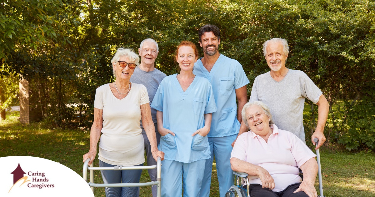 2 caregivers and seniors smile while in a group representing how caregivers can facilitate socialization.