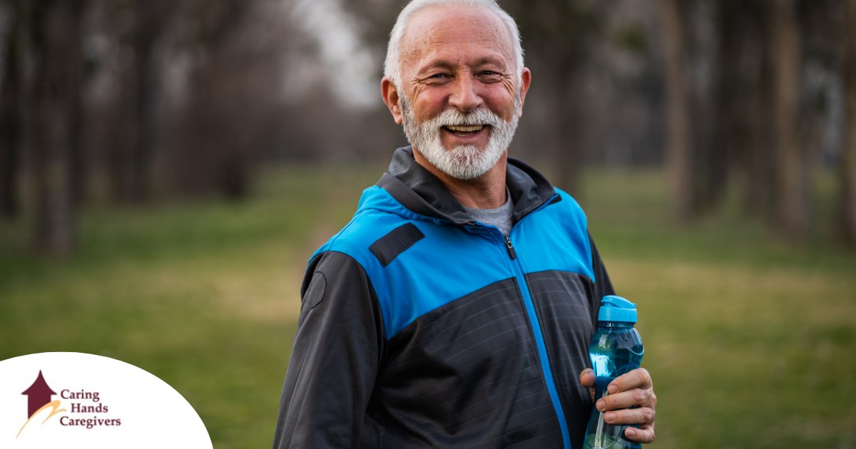 An older man smiles with a water bottle while exercising, representing the benefits of encouraging exercise when caring for seniors at home.