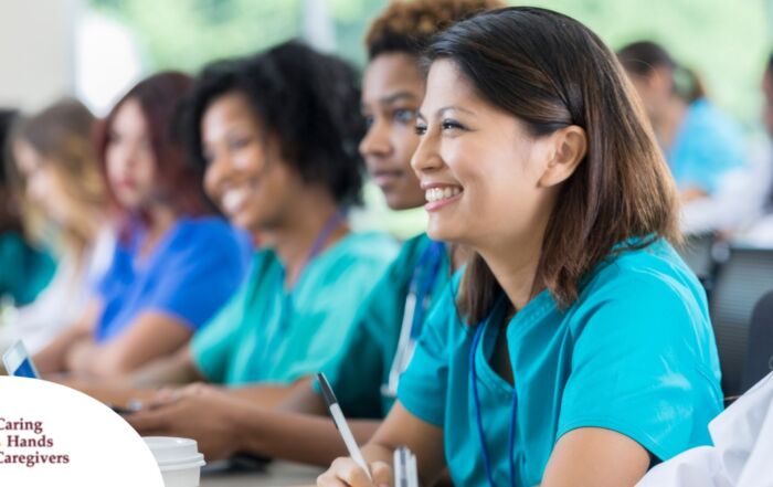 Several students in scrubs happily attend a class, representing caregiver training.