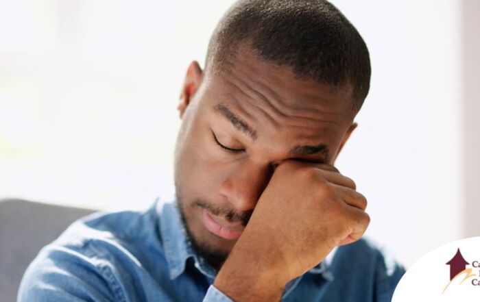 A man tiredly rubs his eyes, representing the exhaustion that can come with family caregiving.