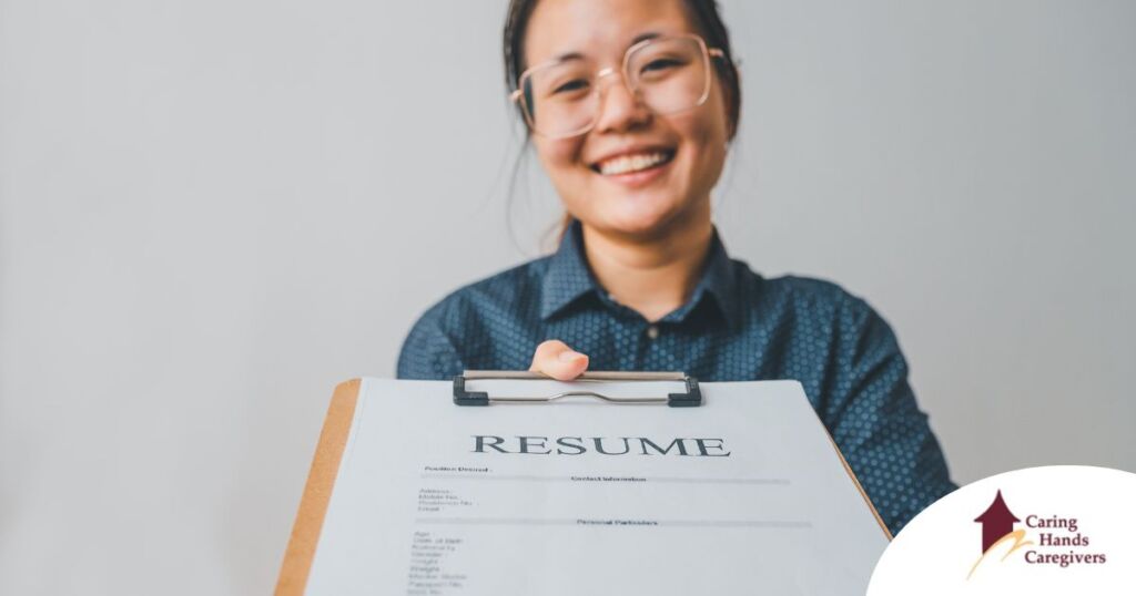 A woman happily hands in a resume, representing a successfully written caregiver resume.