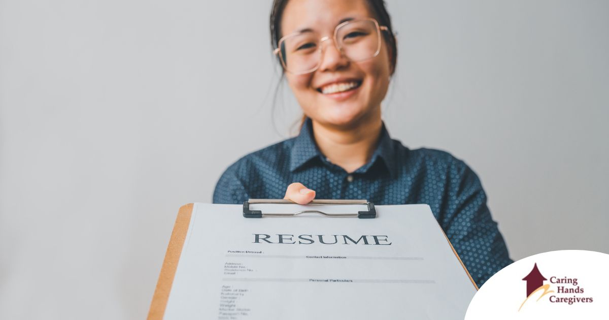 A woman happily hands in a resume, representing a successfully written caregiver resume.